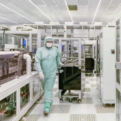 Person in Schutzkleidung in einer modernen industriellen Reinraumumgebung, Symbolbild zum Halbleiteranlagenbau von Aixtron.