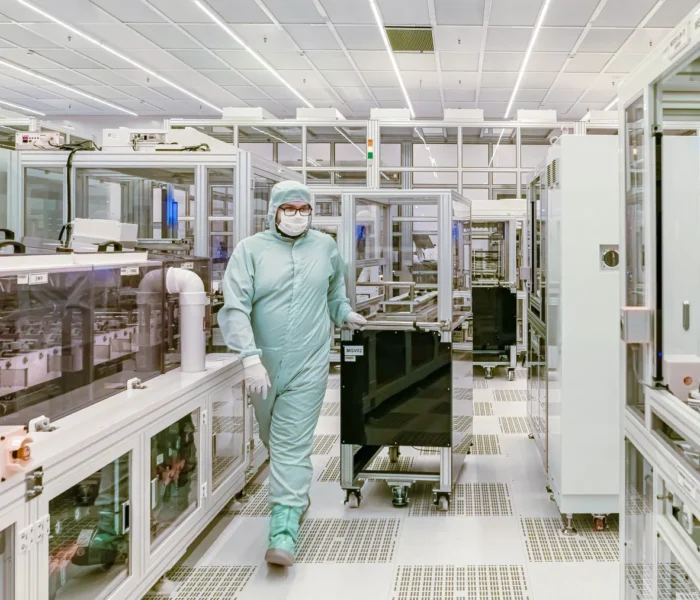 Person in Schutzkleidung in einer modernen industriellen Reinraumumgebung, Symbolbild zum Halbleiteranlagenbau von Aixtron.