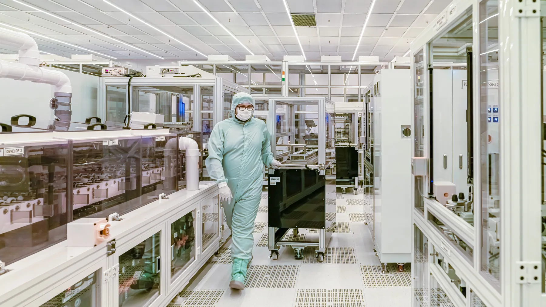 Person in Schutzkleidung in einer modernen industriellen Reinraumumgebung, Symbolbild zum Halbleiteranlagenbau von Aixtron.