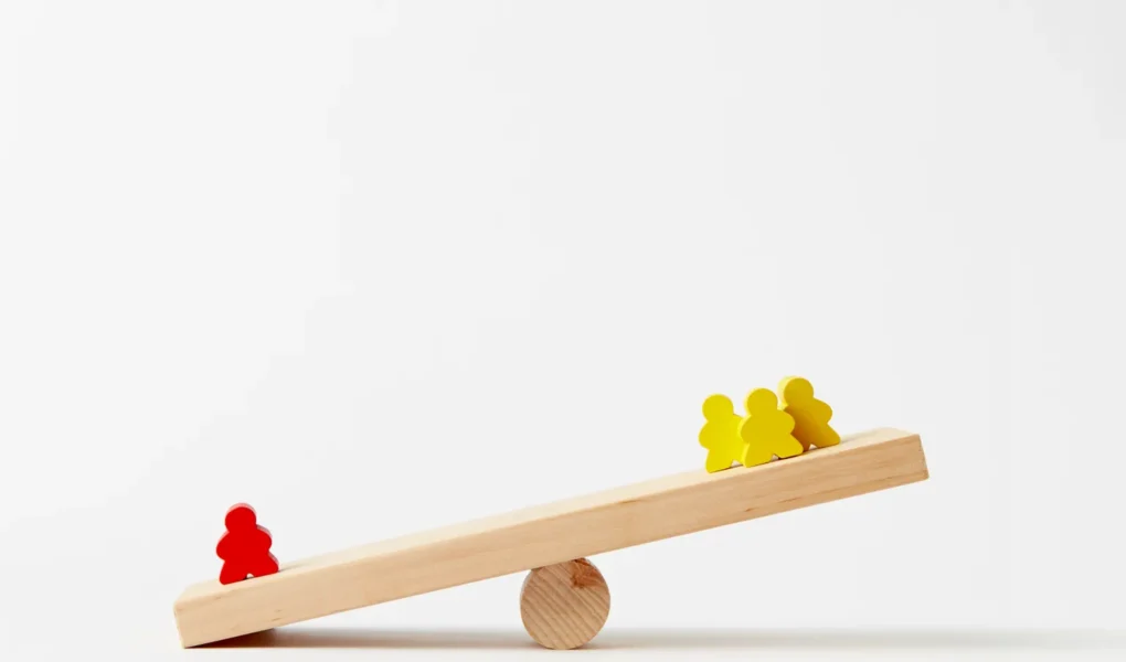 Unterschiedlich verteilte Holzfiguren auf einer Wippe als Symbol für die Gewichtung von Depotpositionen.