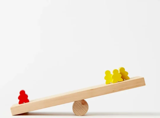 Unterschiedlich verteilte Holzfiguren auf einer Wippe als Symbol für die Gewichtung von Depotpositionen.