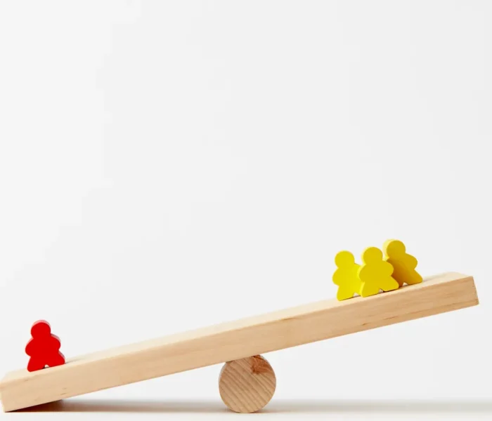 Unterschiedlich verteilte Holzfiguren auf einer Wippe als Symbol für die Gewichtung von Depotpositionen.