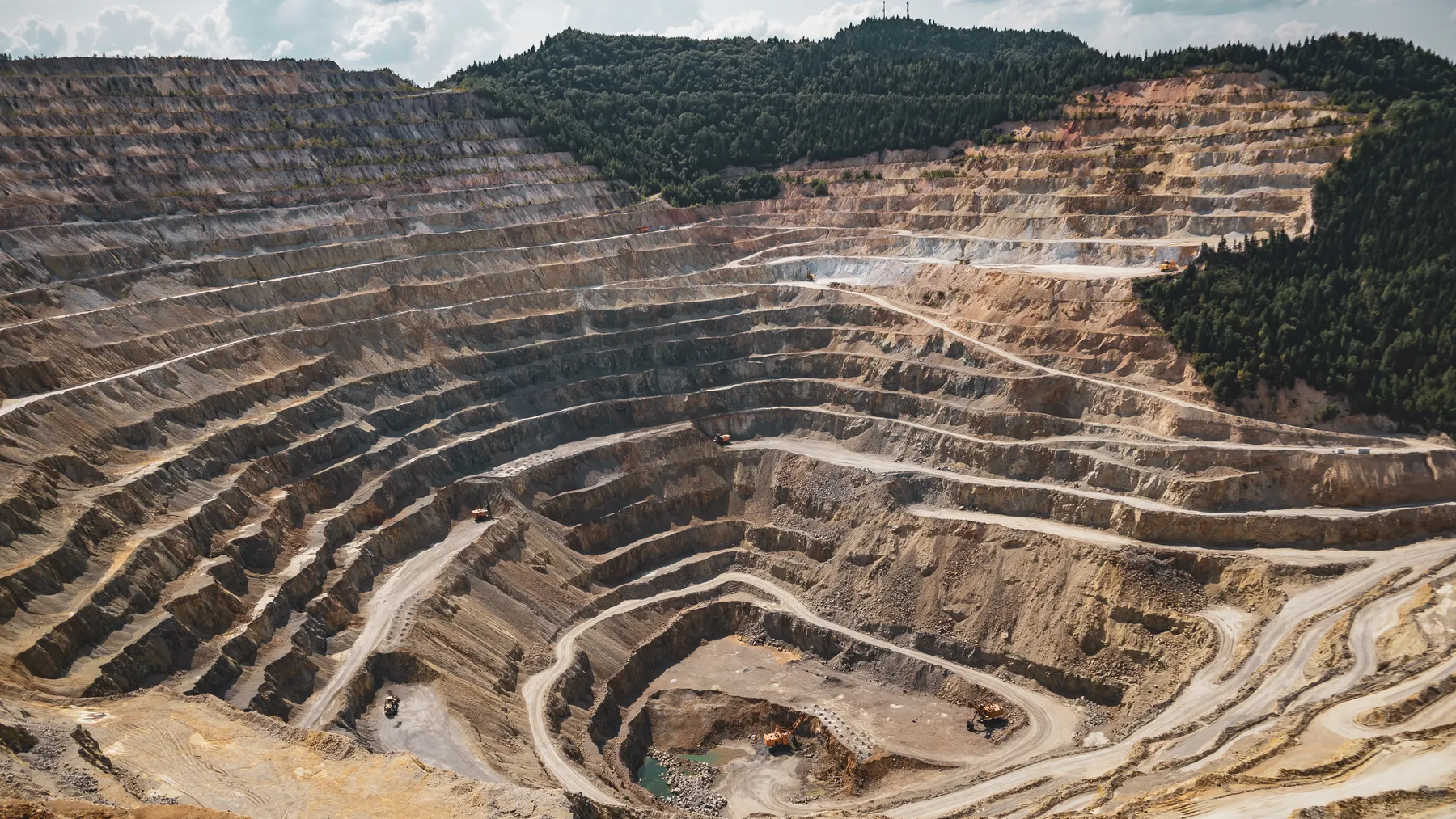 Luftaufnahme eines weitläufigen Tagebaus mit terrassierten Grubenwänden als Symbolbild für die Kupferförderung von BHP.