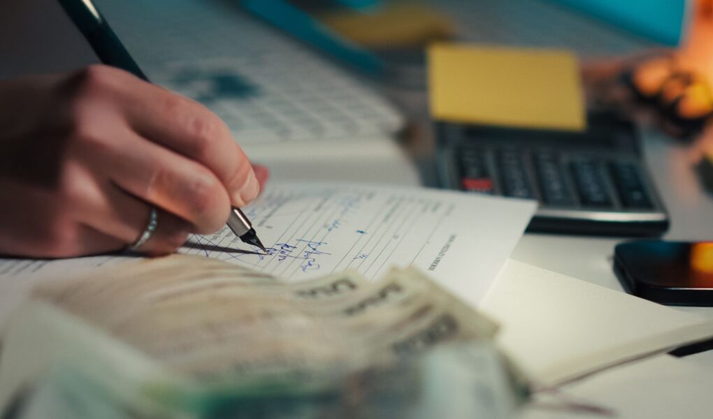 Dunkler Finanzarbeitsplatz mit Rechner und Finanzdokumenten als Symbol für EBITDA, Margen und Unternehmensanalyse.