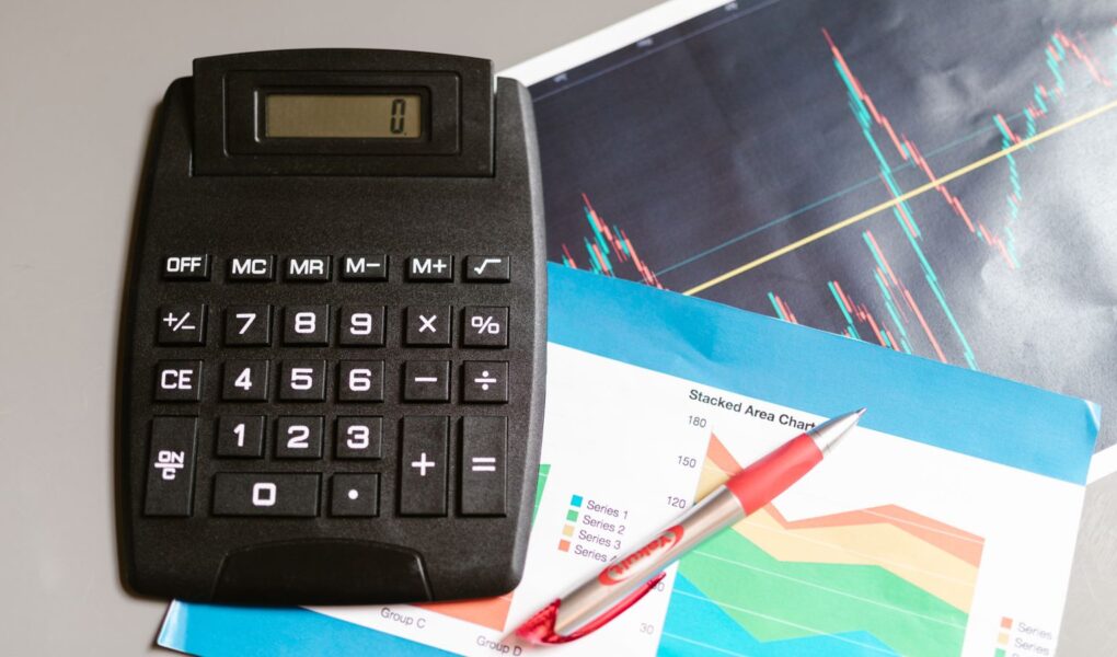 Finanzarbeitsplatz mit Rechner, Stift und Finanzcharts als Symbol für Enterprise Value, Schulden, Cash und Unternehmensbewertung.