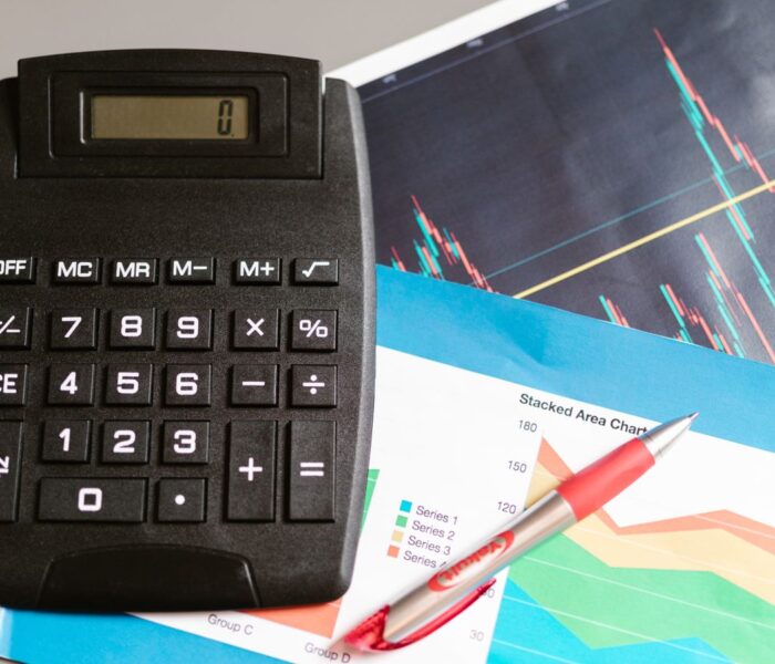 Finanzarbeitsplatz mit Rechner, Stift und Finanzcharts als Symbol für Enterprise Value, Schulden, Cash und Unternehmensbewertung.