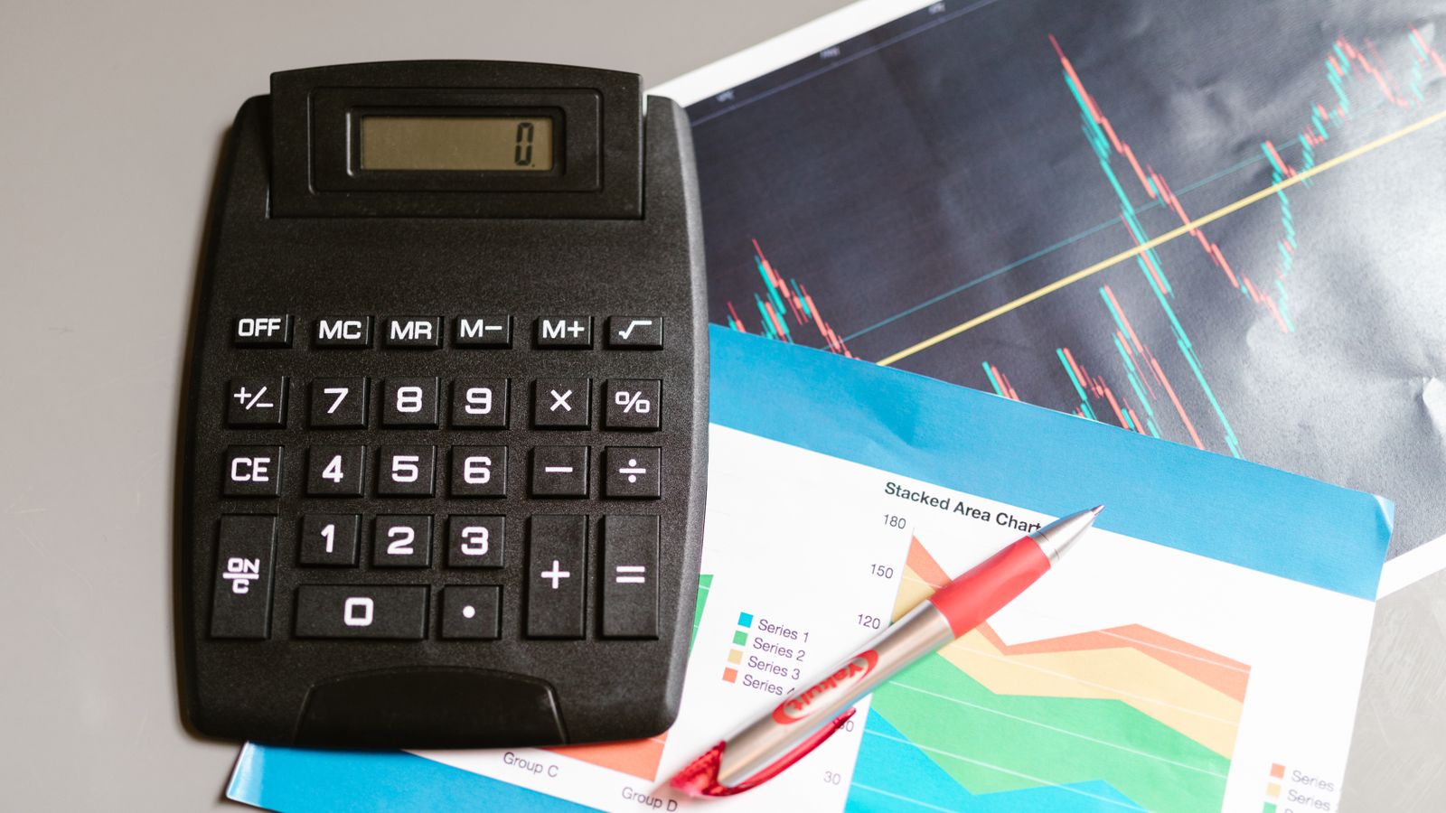 Finanzarbeitsplatz mit Rechner, Stift und Finanzcharts als Symbol für Enterprise Value, Schulden, Cash und Unternehmensbewertung.