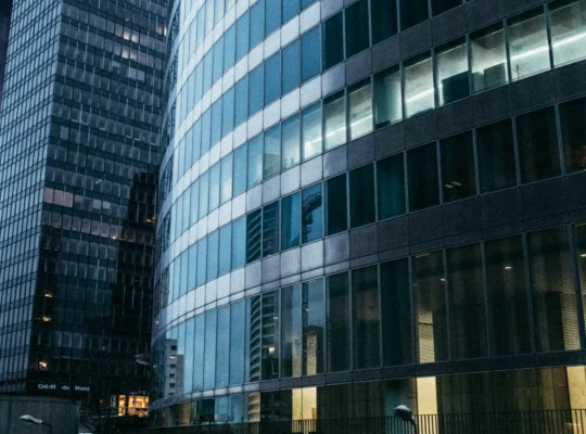 Moderne verglaste Geschäftshochhäuser in der Dämmerung als Symbolbild für die US-Bankenfusion von Fifth Third und Comerica.