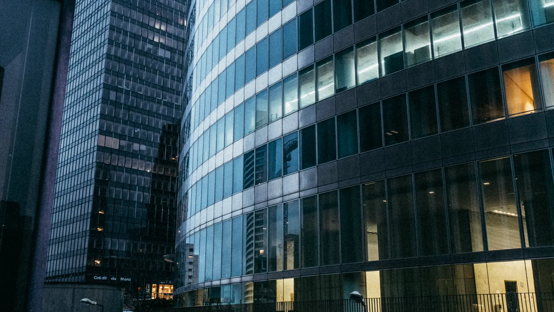 Moderne verglaste Geschäftshochhäuser in der Dämmerung als Symbolbild für die US-Bankenfusion von Fifth Third und Comerica.
