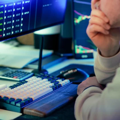 Finanzmarktanalyst an mehreren Computermonitoren mit Kursgrafiken, Symbolbild zum Onlinebroker flatexDEGIRO und seinem Handelsgeschäft.