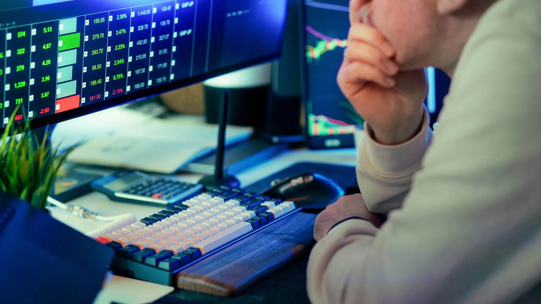 Finanzmarktanalyst an mehreren Computermonitoren mit Kursgrafiken, Symbolbild zum Onlinebroker flatexDEGIRO und seinem Handelsgeschäft.