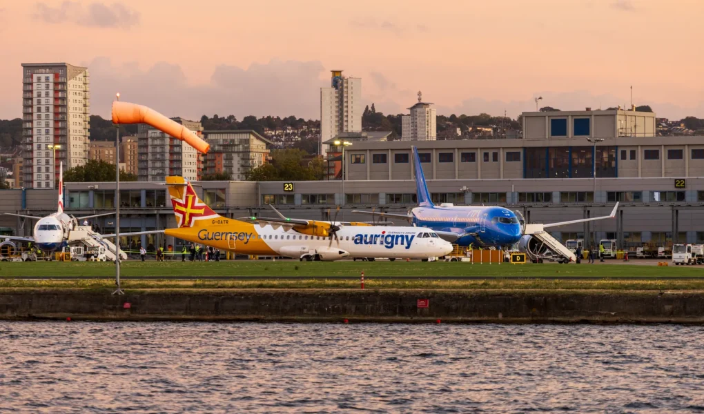 Mehrere Flugzeuge vor einem Flughafenterminal bei Abendlicht mit Stadtpanorama als Motiv für europäische Flughafenbetreiber.