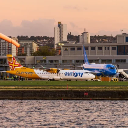 Mehrere Flugzeuge vor einem Flughafenterminal bei Abendlicht mit Stadtpanorama als Motiv für europäische Flughafenbetreiber.