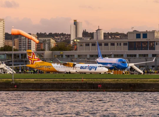 Mehrere Flugzeuge vor einem Flughafenterminal bei Abendlicht mit Stadtpanorama als Motiv für europäische Flughafenbetreiber.