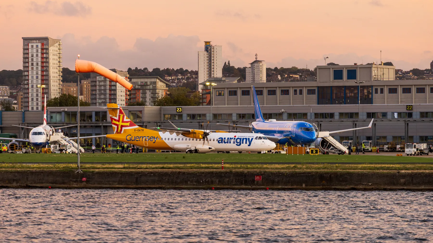 Mehrere Flugzeuge vor einem Flughafenterminal bei Abendlicht mit Stadtpanorama als Motiv für europäische Flughafenbetreiber.