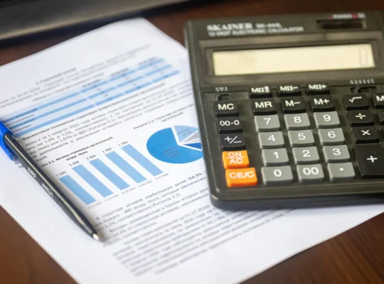 Kalkulator, Finanzbericht und Stift auf einem Schreibtisch als Symbol für die Berechnung der Free-Cashflow-Rendite von Aktien.