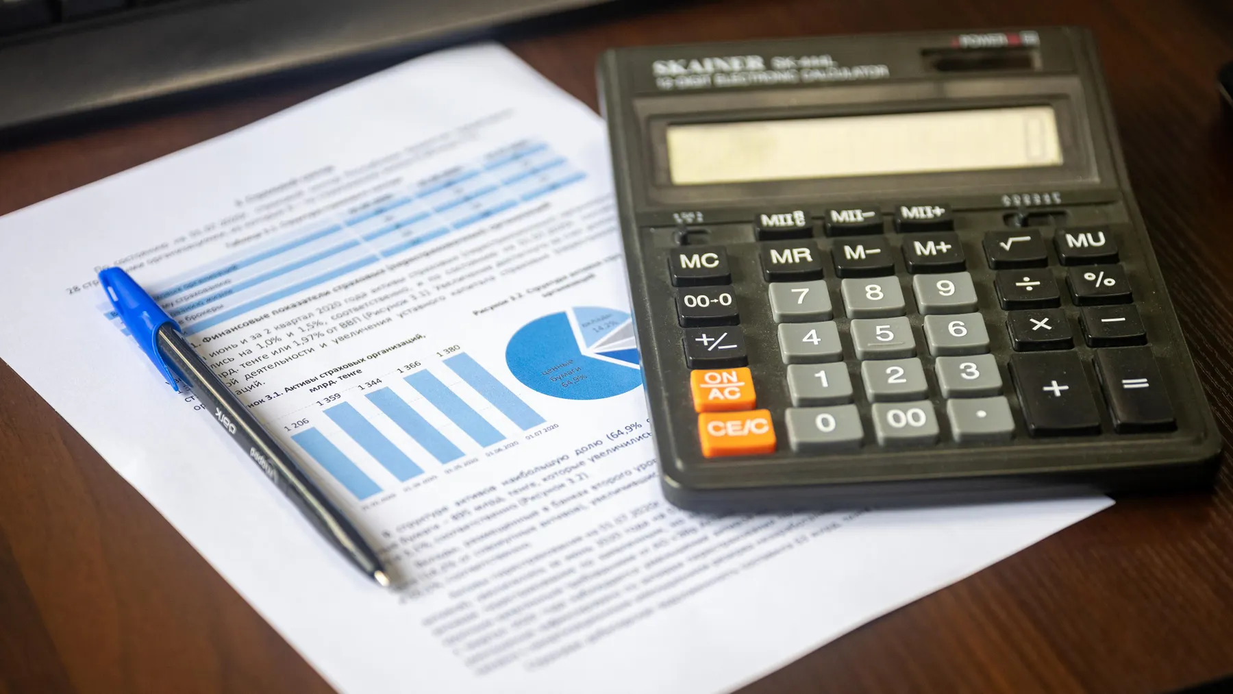 Kalkulator, Finanzbericht und Stift auf einem Schreibtisch als Symbol für die Berechnung der Free-Cashflow-Rendite von Aktien.