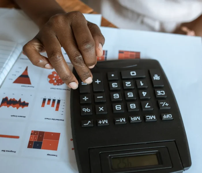 Finanzanalyst berechnet mit einem Taschenrechner Bilanzkennzahlen anhand von Diagrammen und Unterlagen, ohne hinzugefügte Schrift.