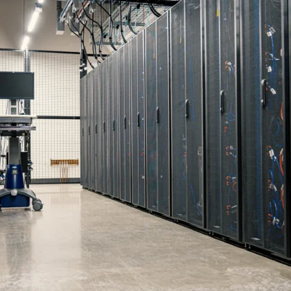 Technischer Gang zwischen Server-Racks und Kabelanlagen eines modernen Rechenzentrums als Motiv für Stromversorgung und Kühltechnik.