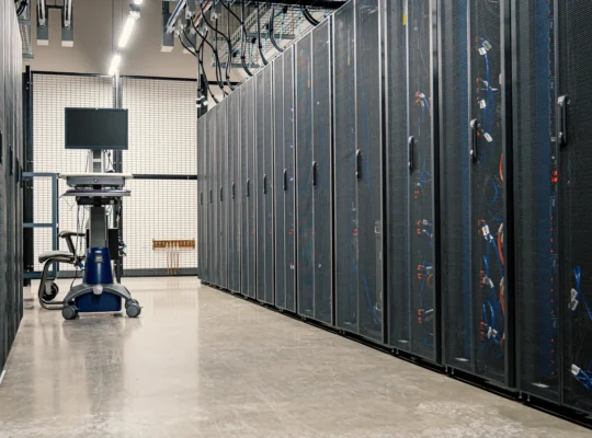 Technischer Gang zwischen Server-Racks und Kabelanlagen eines modernen Rechenzentrums als Motiv für Stromversorgung und Kühltechnik.