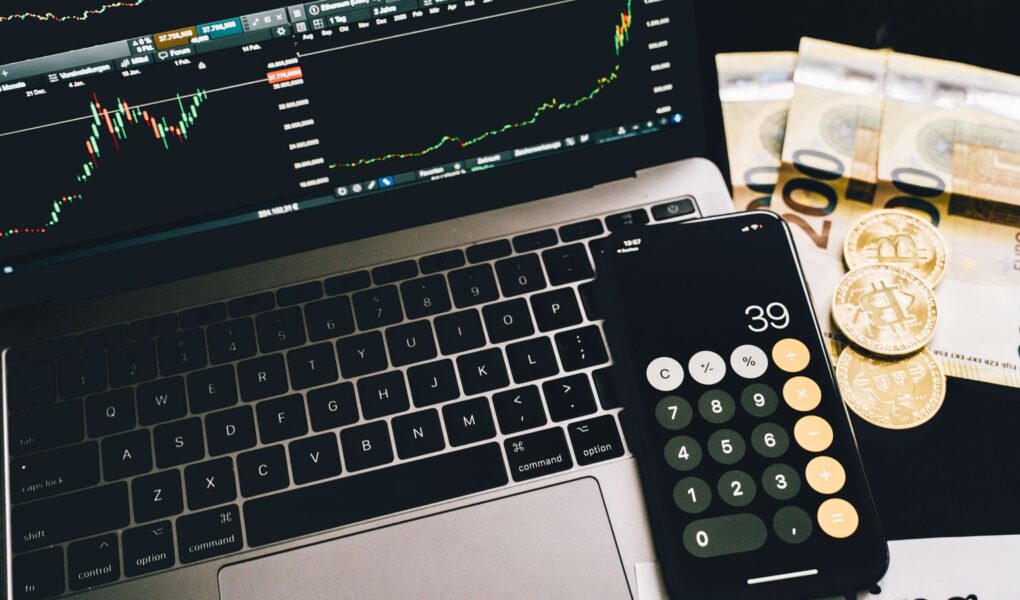 Finanzarbeitsplatz mit Rechner, Marktcharts und Geld als Symbol für Nettoverschuldung, EBITDA und Schuldentragfähigkeit.