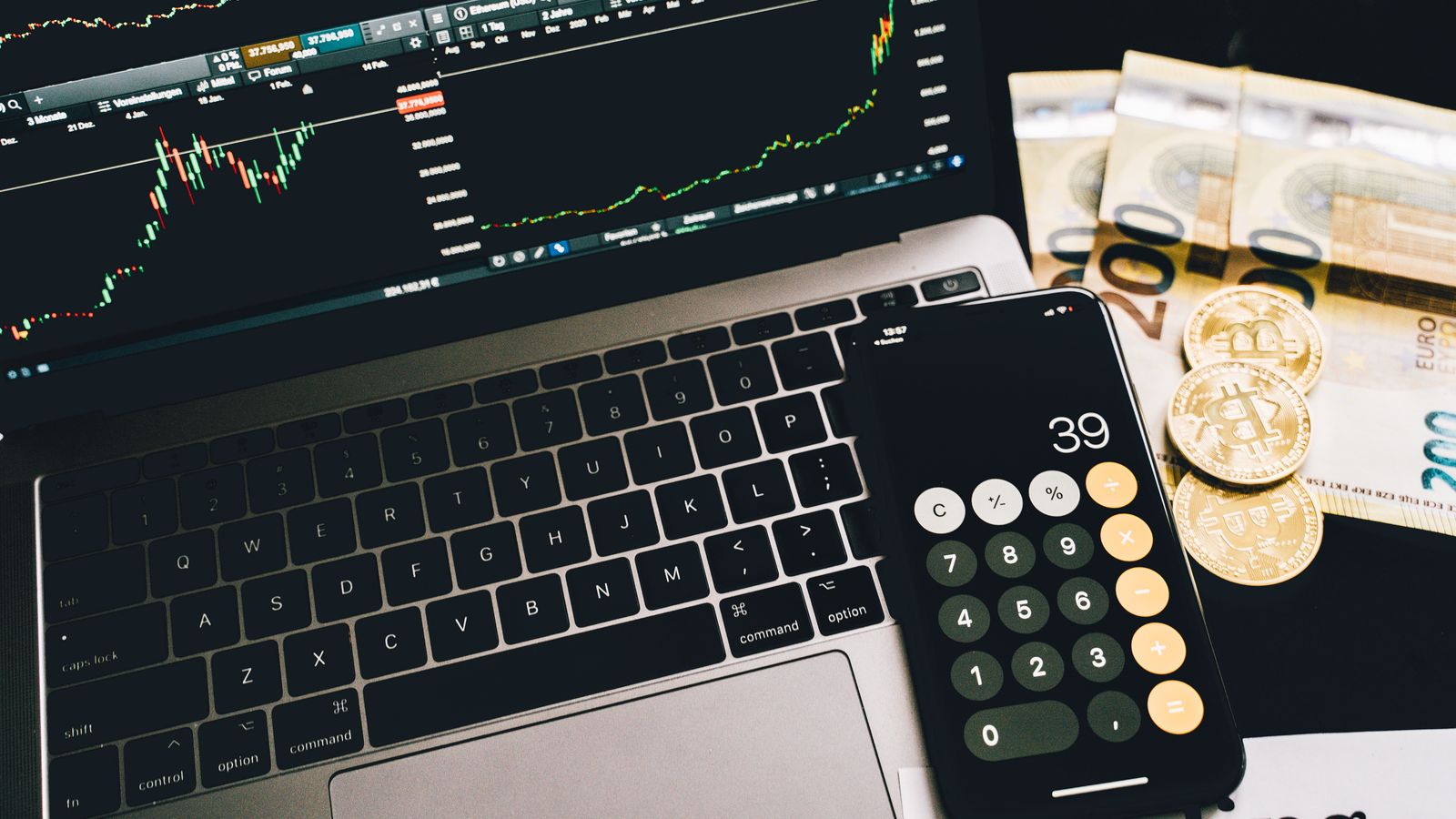 Finanzarbeitsplatz mit Rechner, Marktcharts und Geld als Symbol für Nettoverschuldung, EBITDA und Schuldentragfähigkeit.