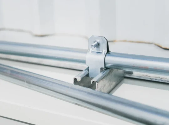 Detailaufnahme einer industriellen Rohrverbindung mit Metallschelle, als Motiv für die NewNORMA-Strategie und Verbindungstechnik.