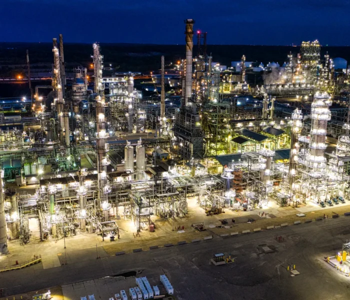 Beleuchtete Erdölraffinerie bei Nacht mit weitläufigen Industrieanlagen, Symbolbild zum Ölpreis und Kerosinkosten 2026.