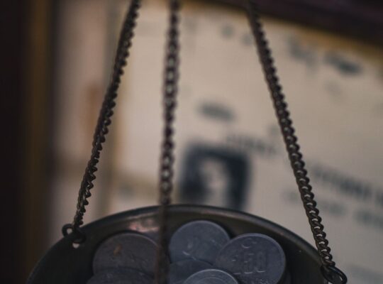 Antike Waage mit Münzen als Symbol für die Neu­gewichtung und Balance eines Portfolios.