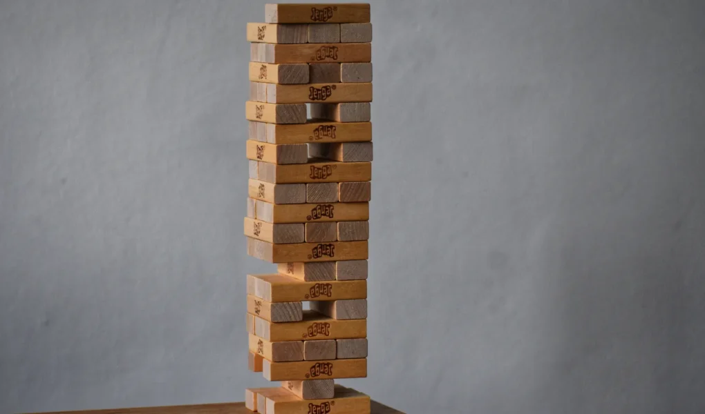 Holzklotzturm mit Lücken in seiner tragenden Struktur als Symbol für die Belastbarkeit eines Portfolios.