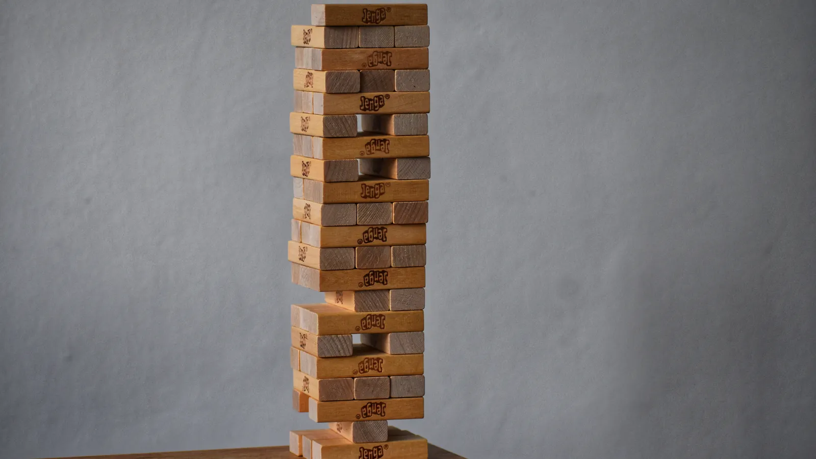 Holzklotzturm mit Lücken in seiner tragenden Struktur als Symbol für die Belastbarkeit eines Portfolios.