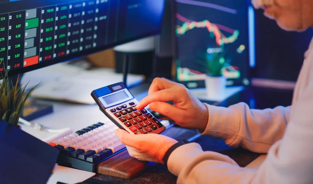 Finanzanalyst berechnet Unternehmenskennzahlen an einem Schreibtisch mit Diagrammen und Rechner; Symbol für Kapitalkosten und WACC.