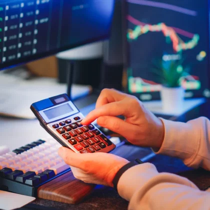 Finanzanalyst berechnet Unternehmenskennzahlen an einem Schreibtisch mit Diagrammen und Rechner; Symbol für Kapitalkosten und WACC.