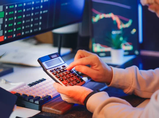 Finanzanalyst berechnet Unternehmenskennzahlen an einem Schreibtisch mit Diagrammen und Rechner; Symbol für Kapitalkosten und WACC.