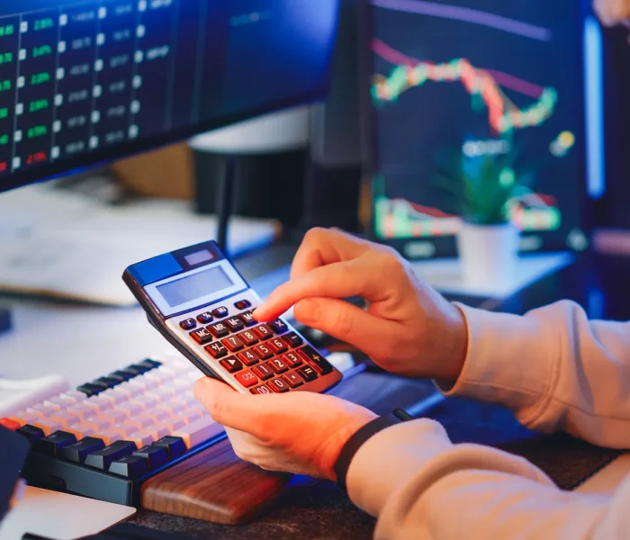 Finanzanalyst berechnet Unternehmenskennzahlen an einem Schreibtisch mit Diagrammen und Rechner; Symbol für Kapitalkosten und WACC.