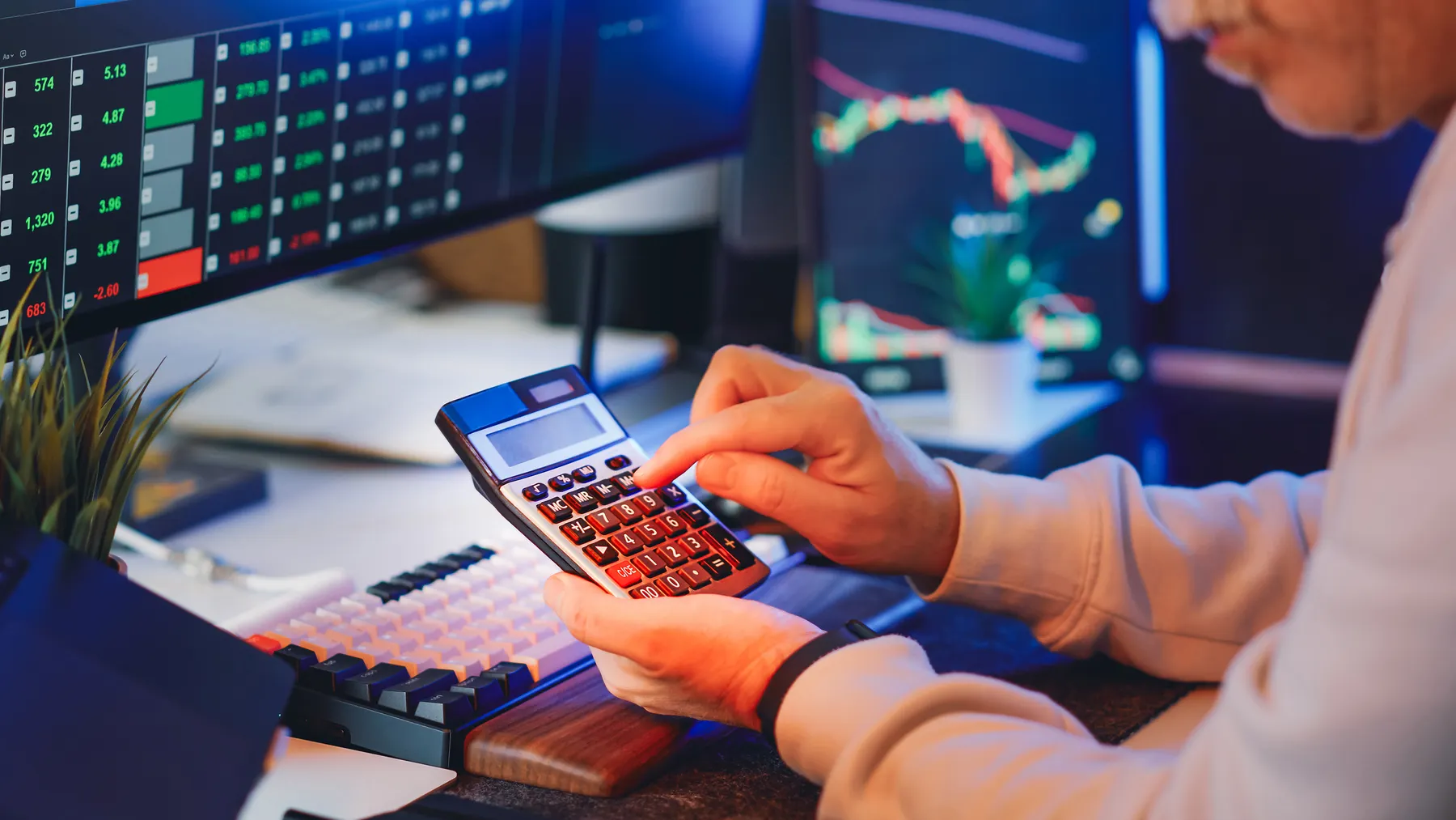 Finanzanalyst berechnet Unternehmenskennzahlen an einem Schreibtisch mit Diagrammen und Rechner; Symbol für Kapitalkosten und WACC.